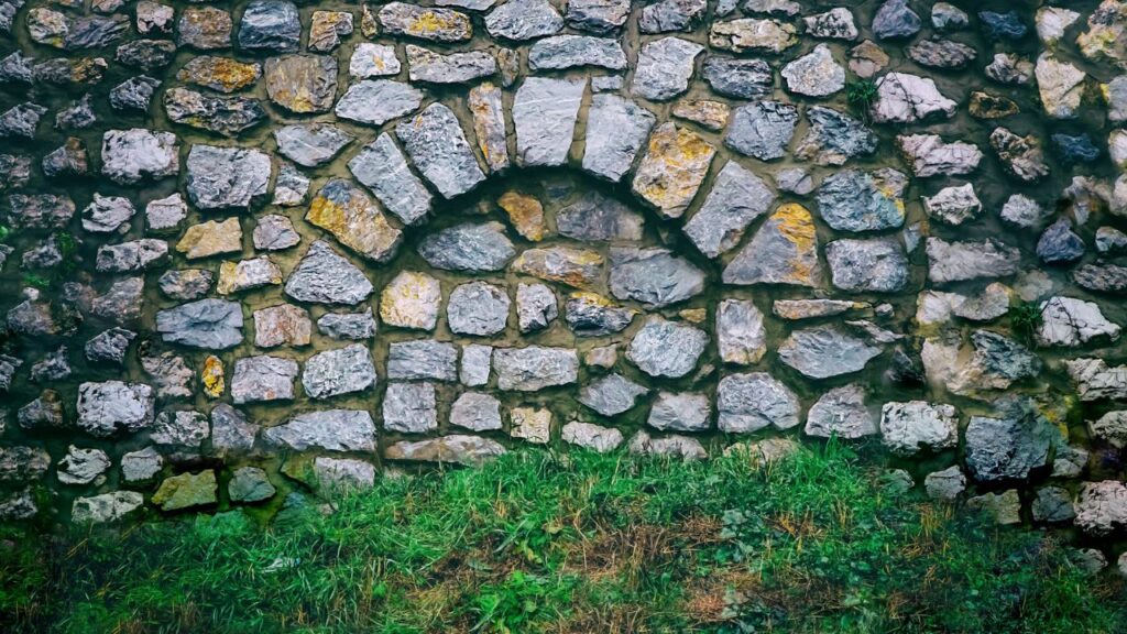緑の地面に立つアーチ模様の石造り壁
