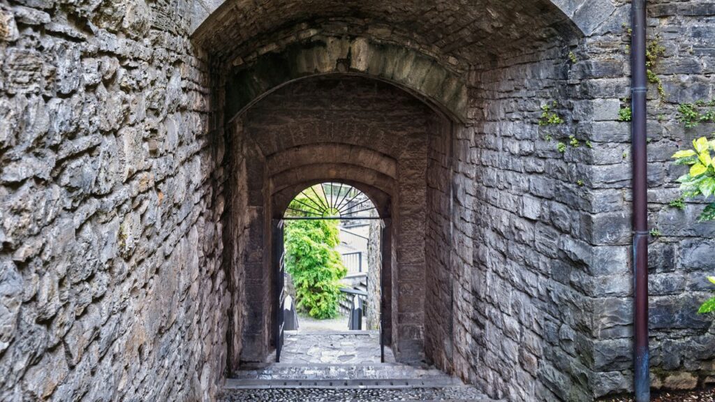 欧州石造建築のアーチ回廊の向こうに新緑